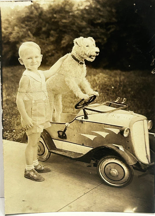ANTIQUE PHOTO OF DOG IN DRIVERS SEAT OF EARLY PEDAL CAR WITH BOY STANDING