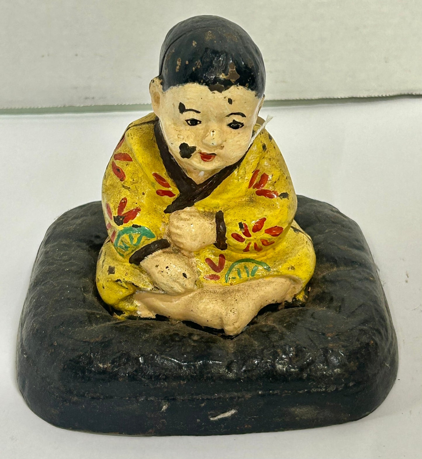 ANTIQUE CAST IRON DOORSTOP OF TAKEO ON CUSHION